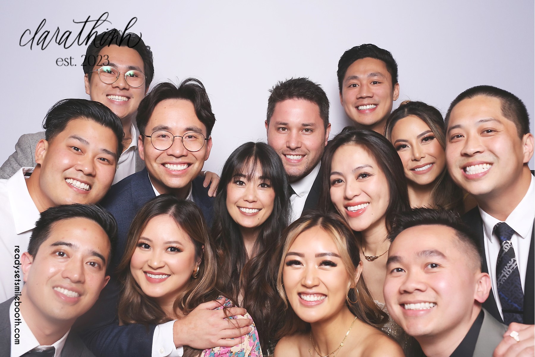 A large wedding group smiling together in the photo booth